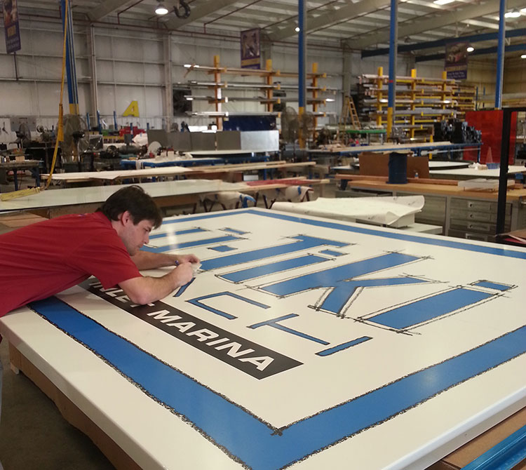 man cutting vinyl on a sign, sign manufacturing